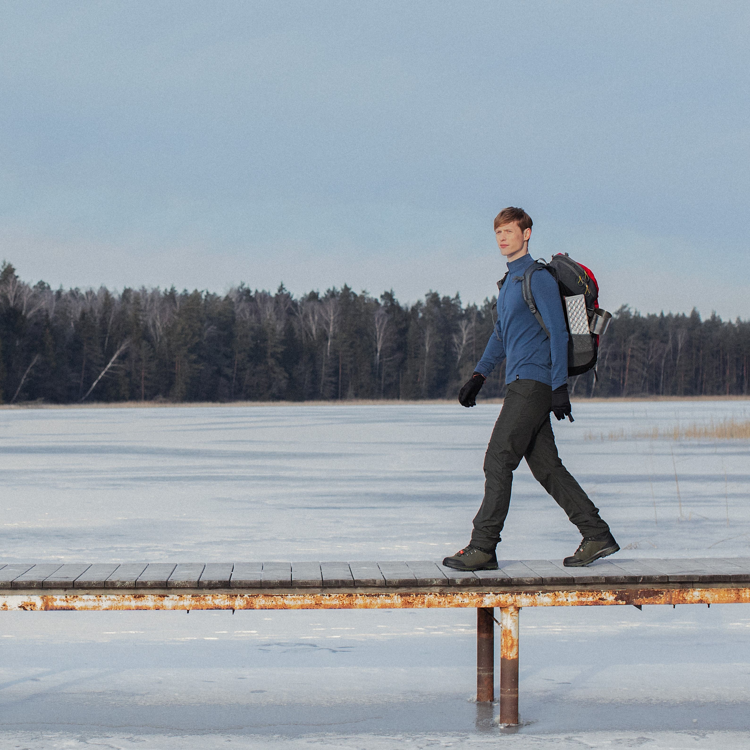 A man goes on a footbridge above a frozen lake